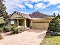 One-story home with light brown siding, a brick paved driveway, and well-manicured landscaping at 5308 Sanderling Ridge Dr, Lithia, FL 33547