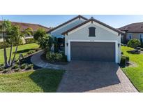 Single-story home with a two-car garage and landscaped yard at 10338 Highland Park Pl, Palmetto, FL 34221