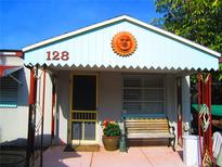 Cute cottage with a whimsical sun facade, covered porch, and charming front yard at 128 121St Ave, Treasure Island, FL 33706