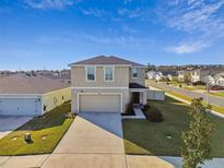 Two-story house with a beige exterior, two-car garage, and well-manicured lawn at 38296 Sonnet Landing Ave, Zephyrhills, FL 33540