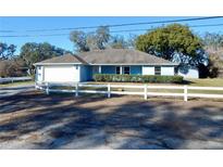 Cute blue house with white fence, attached garage, and large backyard at 37733 Dunbar Ave, Zephyrhills, FL 33542