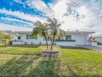 White brick ranch house with teal accents, palm trees, and American flag at 14052 89Th Ave, Seminole, FL 33776