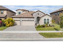 Two-story house with stone accents and a three-car garage at 14136 Swiss Bridge Dr, Riverview, FL 33579