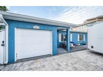 Front view of a charming blue house with a white garage door and a spacious front yard at 17744 1St E St, Redington Shores, FL 33708