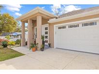 Tan house with white garage door and columns; landscaped front yard at 1912 W Jean St, Tampa, FL 33604