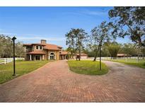 Brick driveway leads to a two-story house with a red tile roof and landscaping at 249 Dogwood Trce, Tarpon Springs, FL 34688