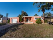 Cute pink house with a single car garage and a well-manicured lawn at 5611 8Th N Ave, St Petersburg, FL 33710