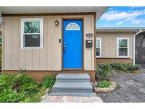 Inviting home exterior with a bright blue door and well-maintained landscaping at 1230 32Nd N St, St Petersburg, FL 33713