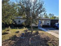 Tan one-story house with blue door, landscaping, and driveway at 1230 32Nd N St, St Petersburg, FL 33713