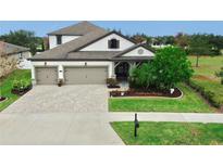 Two-story house with three car garage, landscaped yard, and paver driveway at 12314 Bay Estuary Bnd, Riverview, FL 33579
