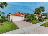 Single-story home with a white garage door, landscaping, and brick driveway at 4936 Sandy Brook Cir, Wimauma, FL 33598