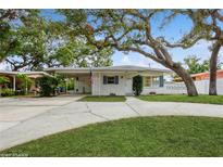 White mid-century modern home with carport and mature landscaping at 51 Lexington Dr, Dunedin, FL 34698