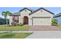 One-story home with red doors, shutters, and paver driveway at 6032 Milestone Dr, Apollo Beach, FL 33572