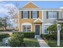 Two-story townhome with yellow and gray exterior, landscaping, and walkway at 1241 Redondo Way, Wesley Chapel, FL 33543