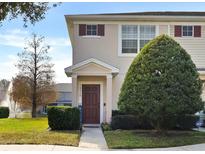 Tan two-story townhome with dark brown door, landscaping, and a walkway at 16314 Swan View Cir, Odessa, FL 33556