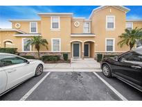 Tan two-story townhome with a gray door and two parking spaces at 1885 Greenwood Valley Dr, Plant City, FL 33563