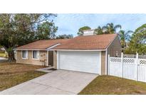 Tan house with white garage door and white privacy fence at 102 Shoreview Ln, Oldsmar, FL 34677