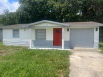 Cute one-story home with gray and white exterior, red door, and attached garage at 4605 Irene Loop, New Port Richey, FL 34652