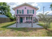 Pink two-story house with green trim, front porch, and pergola at 5901 N Cherokee Ave, Tampa, FL 33604