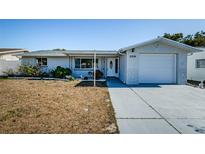 Ranch-style home with a white exterior, attached garage, and a well-maintained lawn at 11214 Glover Rd, Port Richey, FL 34668