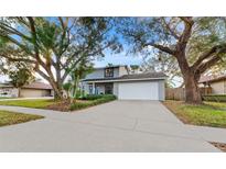 Gray two-story house with a white garage door and landscaping at 16013 Eagle River Way, Tampa, FL 33624