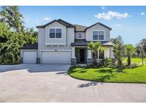 Two-story house with three-car garage, stone accents and lush landscaping at 18437 Purple Creek Ln, Lutz, FL 33549