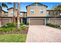 Tan two-story townhome with brown garage doors and landscaping at 28523 Pleasant Bay Loop, Wesley Chapel, FL 33543