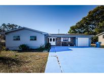 Ranch style home with brick entryway, attached garage, and large driveway at 4573 Deltona Blvd, Spring Hill, FL 34606