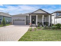 Gray two-story house with gray roof, paver driveway, and covered porch at 4661 Southern Valley Loop, Brooksville, FL 34601