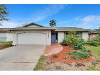 Inviting home exterior featuring a landscaped yard and attached garage at 5810 Ne Venetian Blvd, St Petersburg, FL 33703