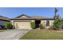 Tan house with a two-car garage and landscaping at 637 Chatham Walk Dr, Ruskin, FL 33570