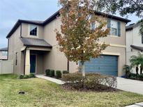Two-story house with gray garage door and manicured lawn at 6325 Yellow Buckeye Dr, Riverview, FL 33578