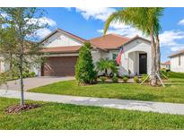 One-story home with brown garage door, tile roof, and landscaped yard at 17217 Sparrow Case St, Wimauma, FL 33598