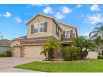 Two-story house with a three-car garage, landscaping, and palm trees at 1737 Fox Grape Loop, Lutz, FL 33558