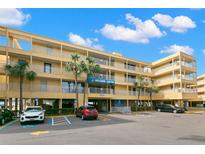 Exterior view of a yellow building with parking and palm trees at 2506 N Rocky Point Dr # 204, Tampa, FL 33607