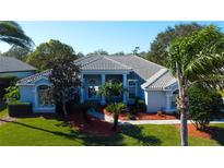 Single-story home with tile roof, manicured lawn, and palm trees at 394 Tall Oak Trl, Tarpon Springs, FL 34688