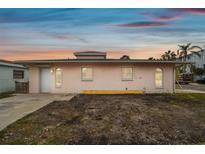 Pink single story home with gray roof, landscaping, and a small yard at 306 180Th E Ave, Redington Shores, FL 33708