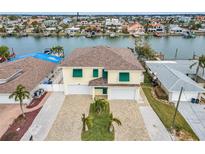 Aerial view of waterfront home with two-car garage and landscaped yard at 11325 5Th E St, Treasure Island, FL 33706