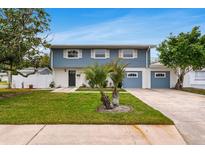 Two-story house with blue siding, white accents, and a two-car garage at 4902 Stolls Ave, Tampa, FL 33615