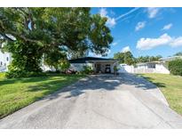 Ranch-style home with carport, mature landscaping, and spacious driveway at 604 Danube Ave, Tampa, FL 33606
