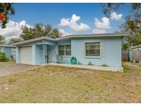 Light blue house with a white garage door and well-manicured lawn at 15073 Harding Ave, Clearwater, FL 33760