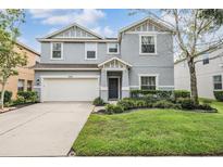 Two-story house with gray siding, white garage door, and landscaping at 2848 Maple Brook Loop, Lutz, FL 33558