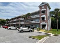 Brick condo building with parking and palm trees at 2461 Rhodesian Dr # 51, Clearwater, FL 33763