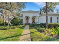 White house with pink door, landscaped yard, and walkway at 2850 Deer Run, Tarpon Springs, FL 34688