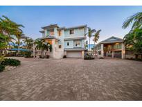 A light blue two story home with a paver driveway and a two car garage at 477 20Th Ave, Indian Rocks Beach, FL 33785