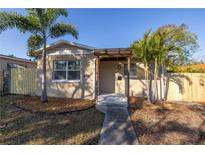 Tan house with wood pergola, walkway, and fenced yard at 5136 16Th N St, St Petersburg, FL 33703