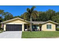 Attractive yellow house with black garage door and palm trees at 1010 Mainsail Way, Palm Harbor, FL 34685