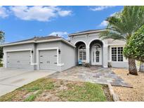 Two-story house with a two-car garage and a stone patio at 214 Bon Vie Pl, Valrico, FL 33594