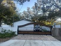 Attractive home with a wood and metal gate, paved driveway, and mature landscaping at 3005 E 148Th Ave, Lutz, FL 33559