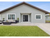 Gray house with a black front door, landscaping, and a small porch at 6509 S West Shore Cir, Tampa, FL 33616
